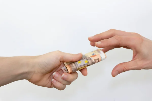 Symbolic representation of financial transaction or exchange with one hand giving and the other receiving rolled 50 euro bills.