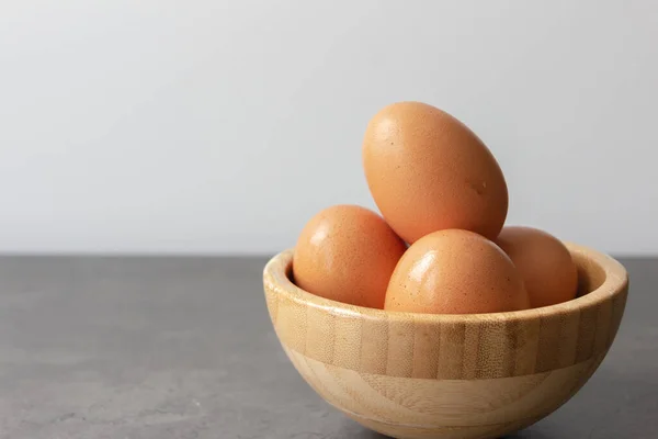 İçine dört taze yumurta istiflenmiş bir bambu kasesi, sol tarafında geniş bir kopya alanı olan gri bir masanın üzerine yerleştirilmiş..