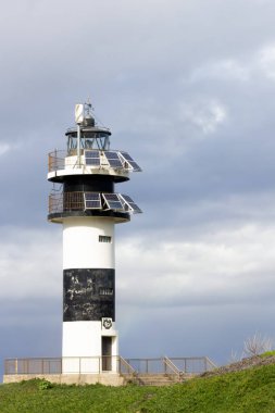 Deniz feneri kıyı manzarası mimarisi. Taş duvarlı geleneksel yapı, bulutlu gökyüzü.