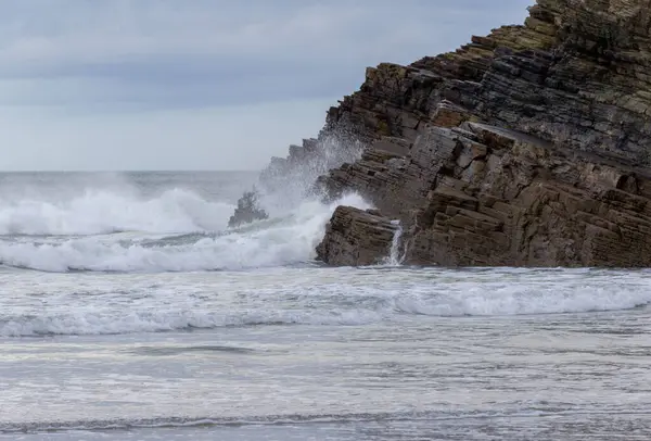 Deniz kenarındaki kayalıklar ve dalgalı denizler. Güçlü okyanus dalgaları engebeli kıyı şeridine çarpıyor. Katedral plajı, Lugo, İspanya