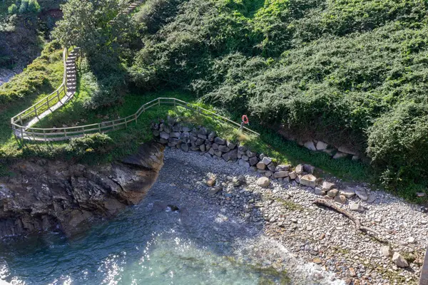 Sahildeki uçurum yolu, güneşli bir öğle vakti deniz kenarında gezinti alanına açılıyor. O Cargadeiro, Ribadeo, İspanya