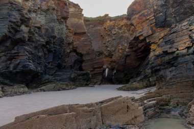 Etrafı engebeli kıyı şeridiyle çevrili yalnız bir yürüyüşçü. Katedrais Sahili, İspanya