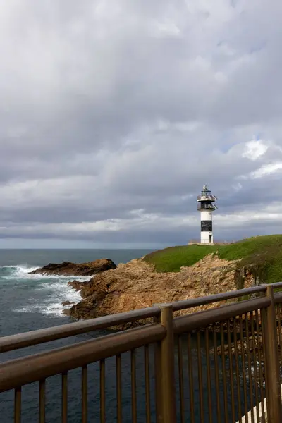 Öğleden sonra deniz feneri kıyı manzaralı sakin okyanus dalgaları ve geçen birkaç bulut. Pancha Adası, Ribadeo, İspanya
