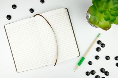 Üst kattaki ofis masasında yatıyordu. Çalışma alanı boş klavye, klavye, ofis malzemeleri, kalem, beyaz arkaplanda yeşil yaprak.