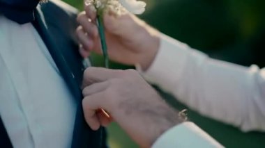 Damadın bir arkadaşı damadın cebine beyaz çiçekler koydu. Damat düğün için hazırlanıyor..