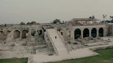 İsrail 'in antik Caesarea şehrinde siyah elbiseli bir kemancı merdivenlerde keman çalar. İnsansız hava aracından video çekimi.
