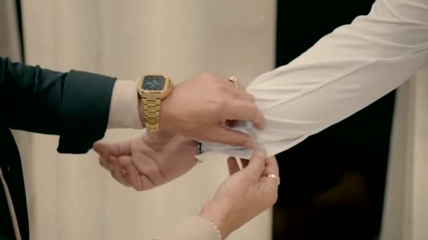 男は他の男の白いエレガントなシャツの袖にボタンを固定する 結婚式の準備 — ストック動画