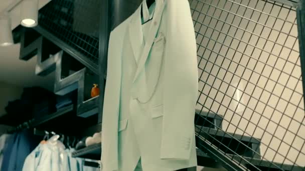 メンズエレガントな衣料品店 メンズストアのハンガーに ライトカラーのスーツが掛かります — ストック動画