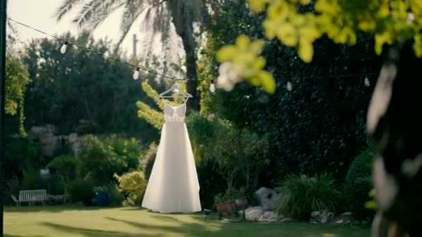 드레스는 정원에서 화환에 있습니다 드레스는 바람에 움직입니다 결혼식을위한 완벽한 정원에서 — 비디오