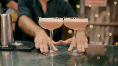the waiter moves two glasses of cocktails towards the guest. Video filmed in slow motion.