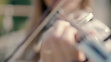 close-up shot of a young girl playing the violin standing in an open area.