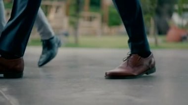 Legs of men wearing elegant shoes walking down the street. Close-up shot in slow motion