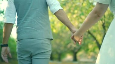 Bride and groom walking hand in hand in a garden. High quality FullHD footage