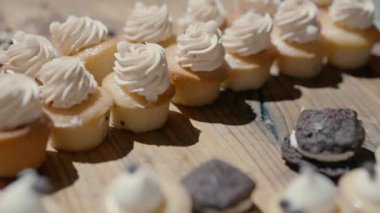 Desserts on the wooden tray Desserts on the wooden tray at the event. Lots of cakes on the table close up slow motion. Small and delicious desserts in the event hall