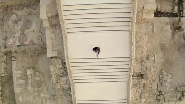 黒いドレスを着たヴァイオリニストが イスラエルの古代都市の階段でバイオリンを演奏します 無人機からのビデオ撮影 イスラエル Caesarea 2022 — ストック動画