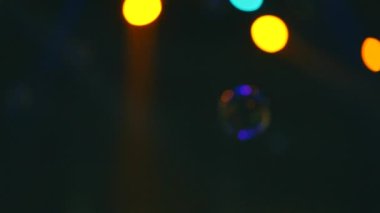 Karanlık bir olay salonunun havasında yanan projektörlerle uçan sabun köpüğü..