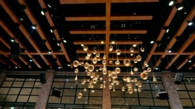 Bir etkinlik salonunun tavanından sarkan ve koridoru aydınlatan güzel altın lambaların yavaş çekim videosu..