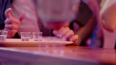 Bir el bardaki müşteriler için iki bardağa alkol dolduruyor. Bir barmen bardaki bardaklara alkol döker.