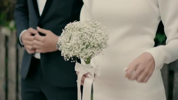 花嫁と新郎がフェンスで一緒に立っています 花嫁は花束を持ってる 結婚式の日に花嫁と新郎の美しいスローモーションビデオ撮影 — ストック動画