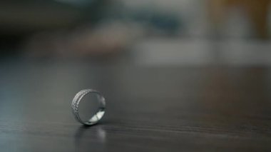 Two wedding rings rotate together on the wooden table. close up video