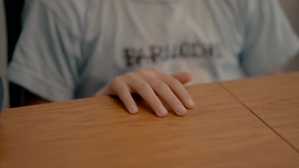 男の子は木のテーブルに座り テーブルの上で指で遊ぶ — ストック動画