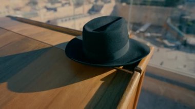 A black Orthodox hat rests on the wooden table in the balcony with a view of the Western Wall in the morning.