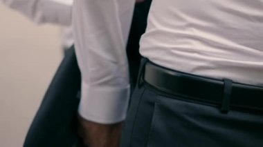 Damadın bir arkadaşı düğün için takım elbise giymesine yardım ediyor..