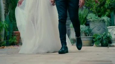 Gelin ve damat el ele tutuşup güzel bir sokakta yürüyorlar..