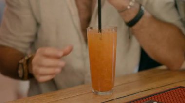Barda beyaz gömlekli bir adam portakal kokteyli içiyor..