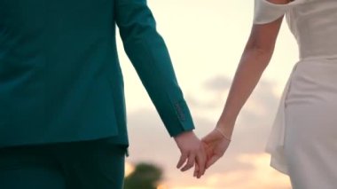 Gelin ve damat gün batımında el ele yürüyorlar. Yüksek kaliteli FullHD görüntüler