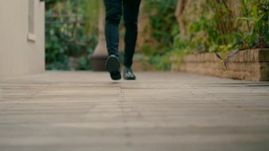 Zarif giyinmiş ve şık siyah ayakkabılar giyen bir adam kameraya doğru yürür. Yavaş çekim.