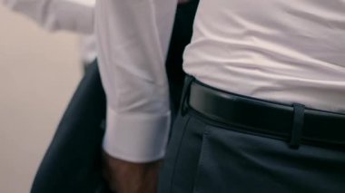 Damadın bir arkadaşı düğün için takım elbise giymesine yardım ediyor..