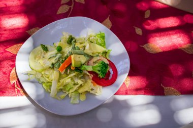 Tabağında peynir ve kırmızı domates olan sebze salatası.