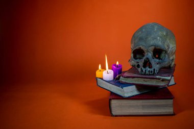Kafatası yanan mum ve kitaplarla