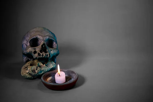 Siyah arka planda yanan mum ve kafatası.