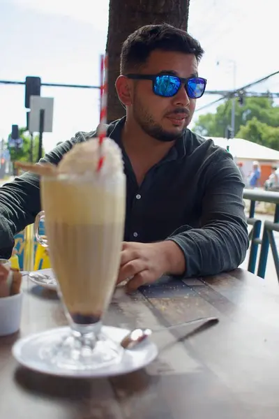 latin person consuming coffee in an outdoor coffee shop