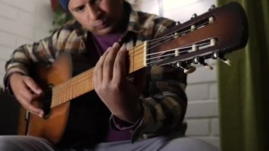 Adam kanepede gitar çalıyor.