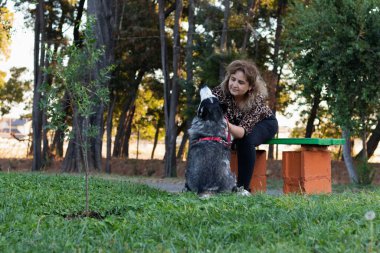 Kadın parkta köpeğini okşar.