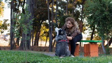 Kadın parkta köpeğini okşar.