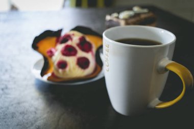 Bir fincan sıcak kahve ve bir dilim çilekli kek.