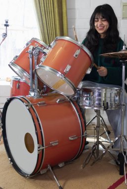Genç kız davul çalışırken gülümsüyor.