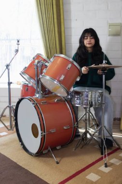 Evinin oturma odasında davul çalan kız.