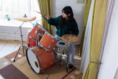 Evinin oturma odasında davul çalan kız.