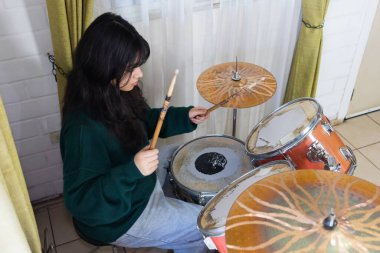 Genç kız davul çalışıyor.