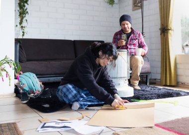 Babası izlerken bir kız karton figürler kesiyor..