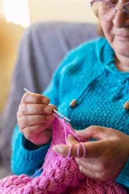 Yaşlı bir kadının elleri örgü örüyor.