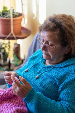 Yaşlı Latin kadın yelek örüyor.