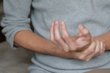 Asian man holding hand with muscle weakness, numbness and paralysis symptoms after vaccination. Guillain Barre syndrome rare cause by autoimmune disorder concept. Selective focus. clipart