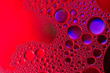 Suyun içindeki ışığı yansıtan yağ halkalarına sahip soyut doku