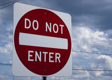 Bulutlu bir arkaplanda, elektrik hatları olan kırmızı ve beyaz Girilmez işareti